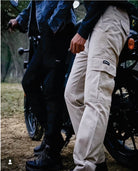 Two people standing next to a motorcycle, one wearing beige cargo pants and the other in dark clothing.