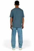 Person wearing a teal t-shirt and blue jeans on a white background
